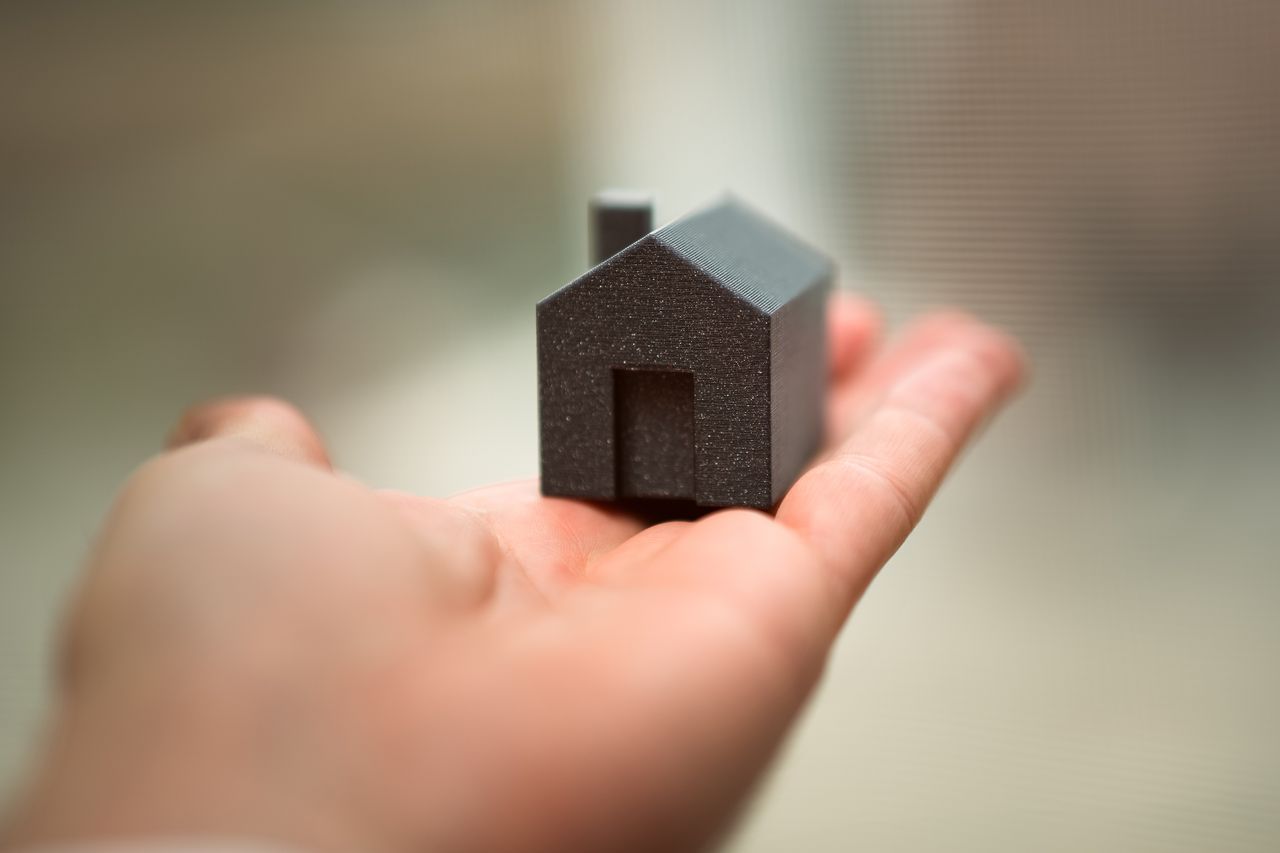 The Art of Drawing Readers In: Your attractive post title goes here Close-up of a hand holding a miniature house model representing real estate concepts like buying or investment.